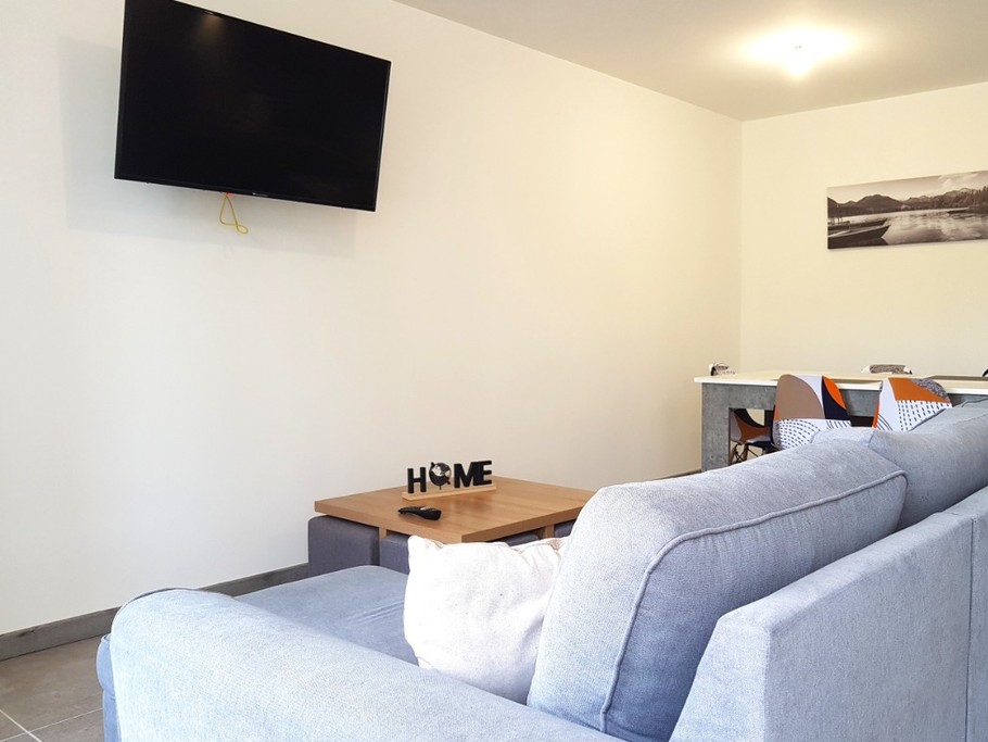 Grande pièce de vie de 32 m² avec coin cuisine toute équipée, coin séjour et coin salon. Accès à la terrasse de plain-pied.