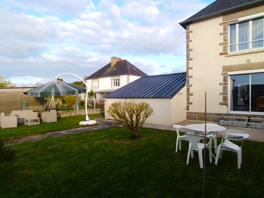 Jardin à l'arrière de la maison avec pelouse, terrasse, 2 salons de jardins haut et bas et parasol. Garage fermé pour stocker vos vélos, poussettes, paddle, etc.