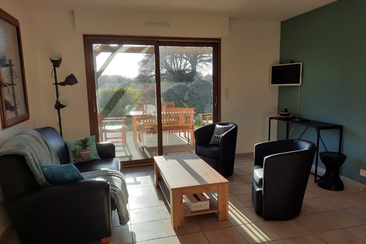 Salon avec baie vitrée donnant sur la terrasse et le jardin