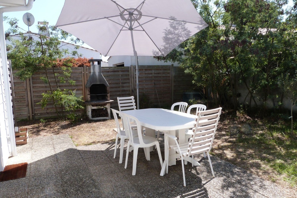 Terrasse avec salon de jardin, parasol et barbecue