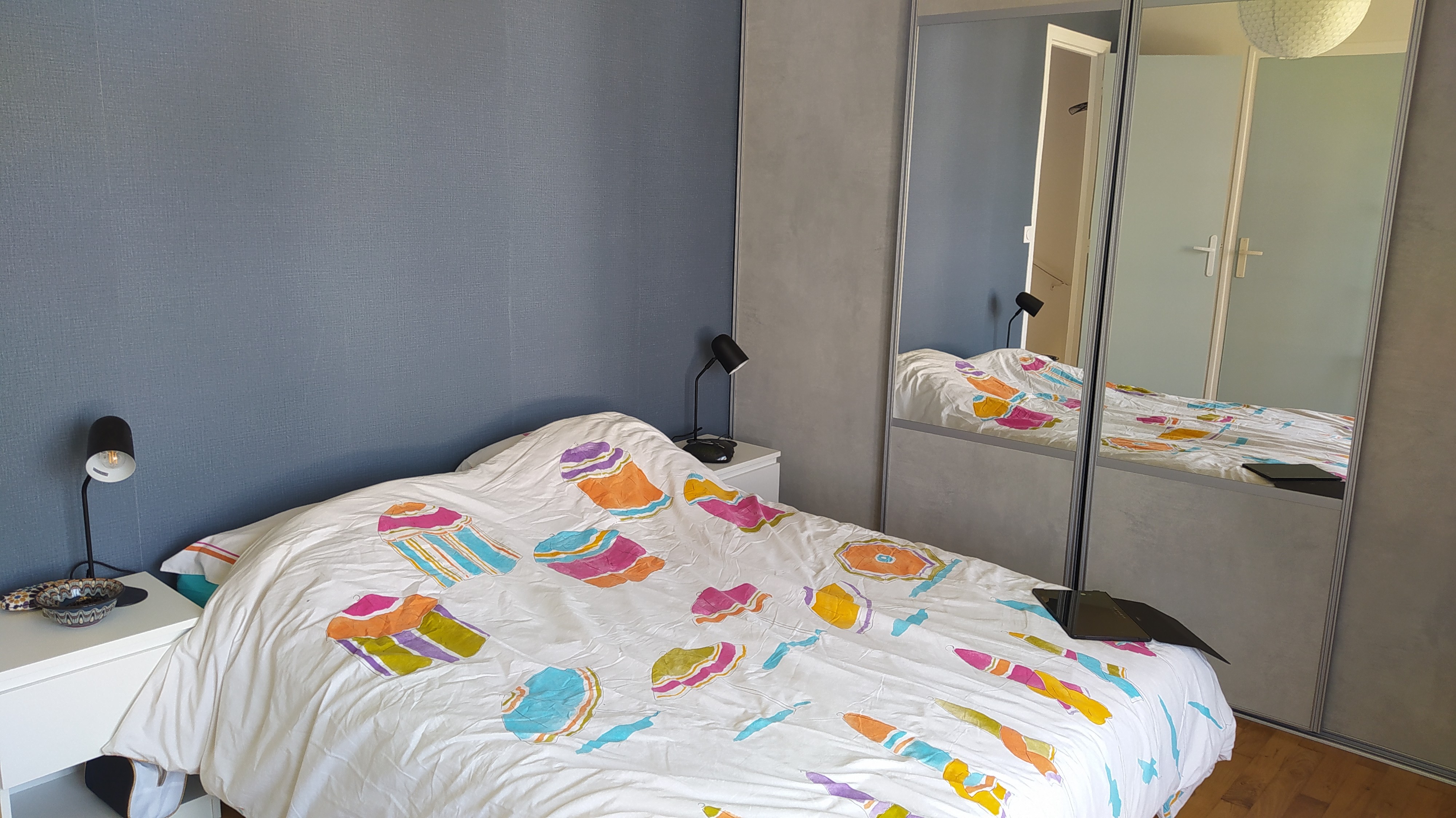 Chambre 1 avec un lit 140 cm, rangements, porte-manteau, et salle d'eau communicante (douche grande dimension et meuble vasque avec miroir)