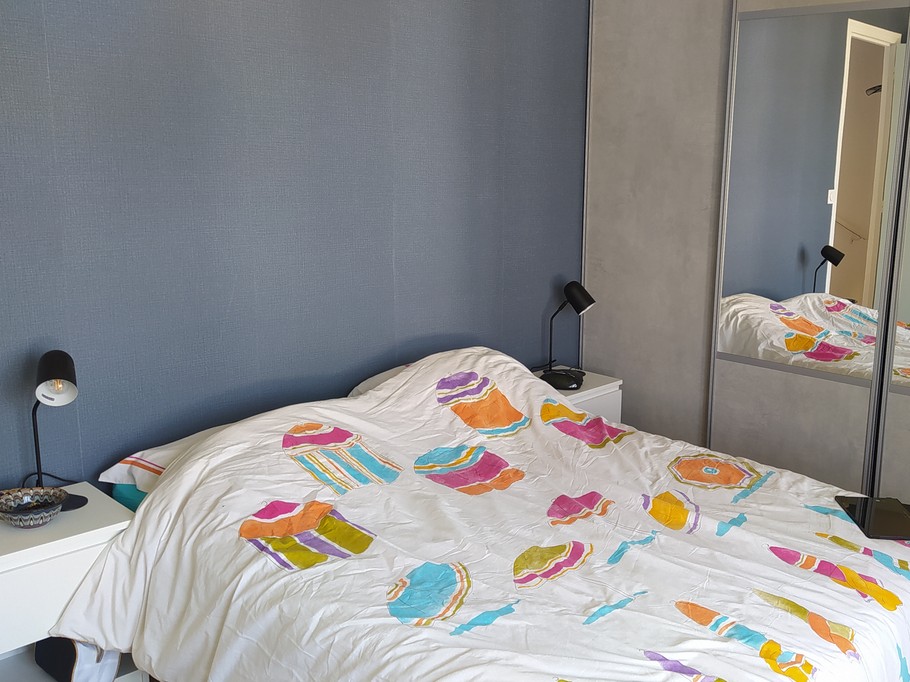 Chambre 1 avec un lit 140 cm, rangements, porte-manteau, et salle d'eau communicante (douche grande dimension et meuble vasque avec miroir)