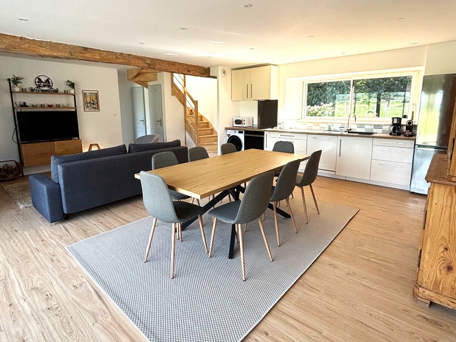 Grande pièce de vie avec salon (poêle à bois, smart TV), séjour et cuisine ouverte parfaitement équipée.