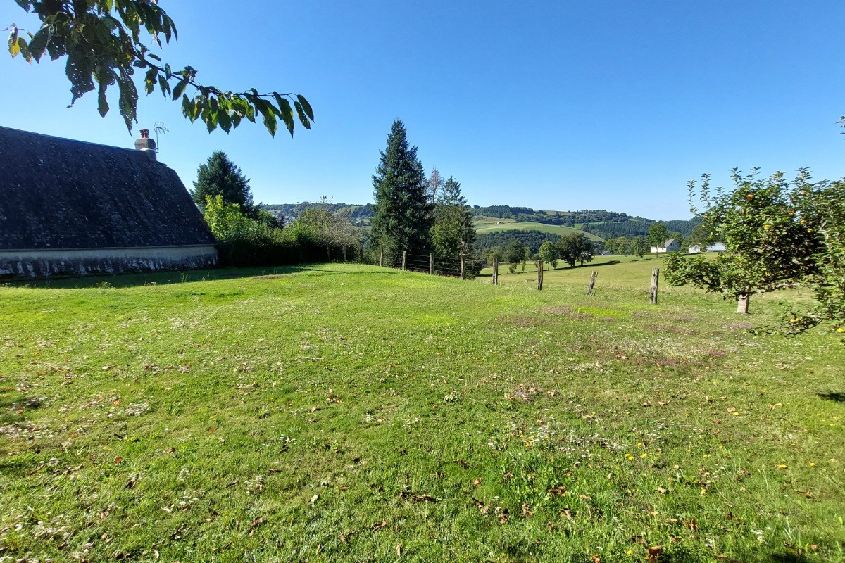 "Grand jardin clos avec vue panoramique sur les montagnes, offrant tranquillité et espace pour se détendre.