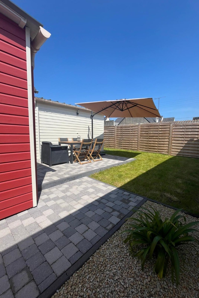 Allée sur le côté de la maison menant à la porte à la terrasse, au jardinet et à la porte d'entrée.