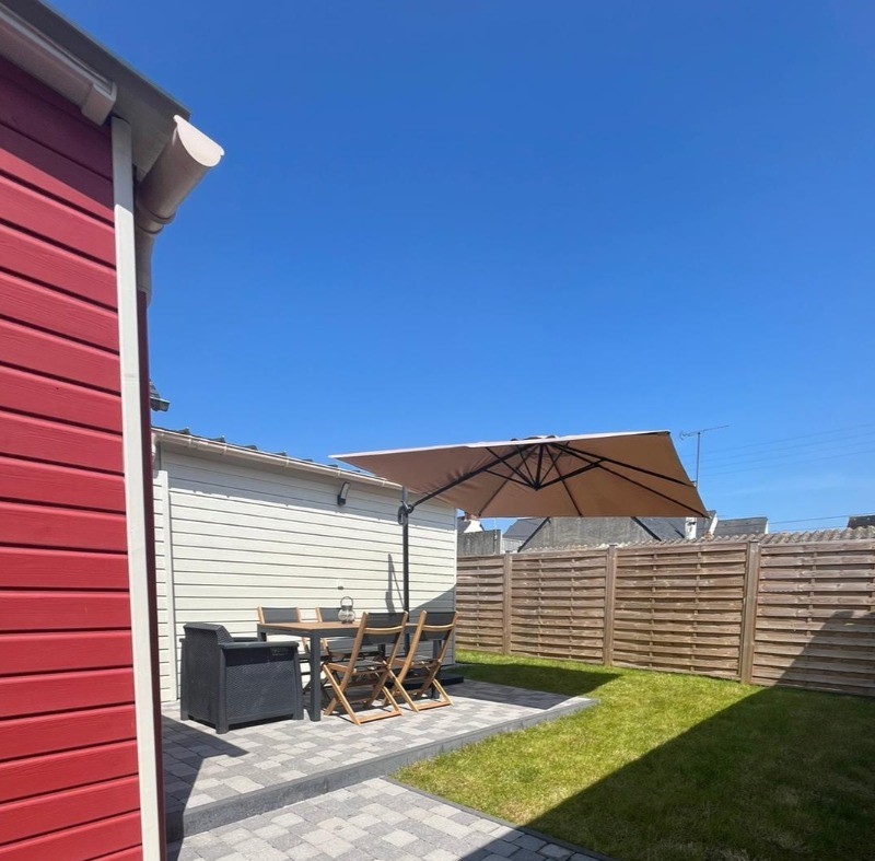 Allée sur le côté de la maison menant à la porte à la terrasse, au jardinet et à la porte d'entrée.