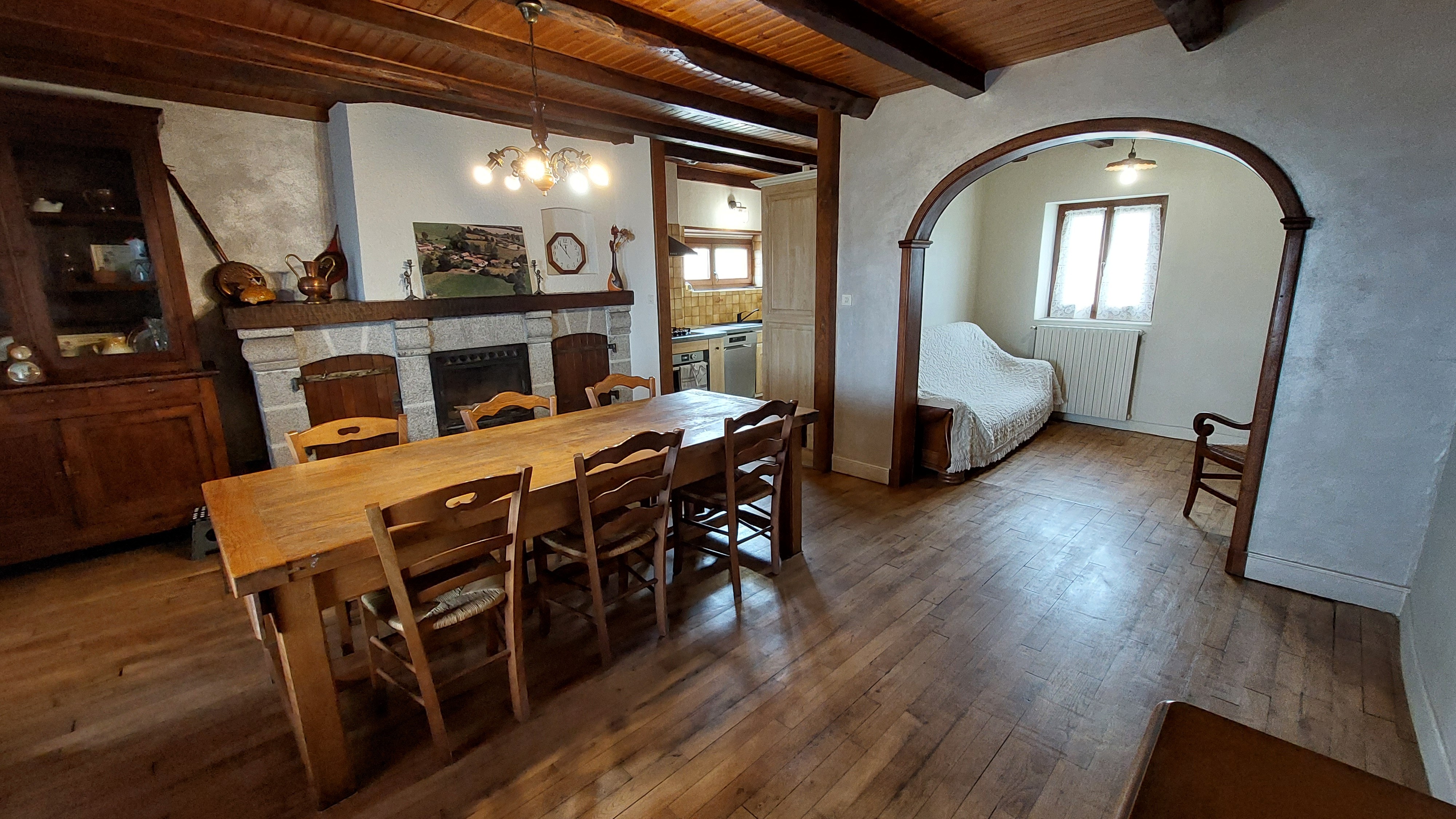 Open-plan living room with arch and wooden furniture in rural gîte