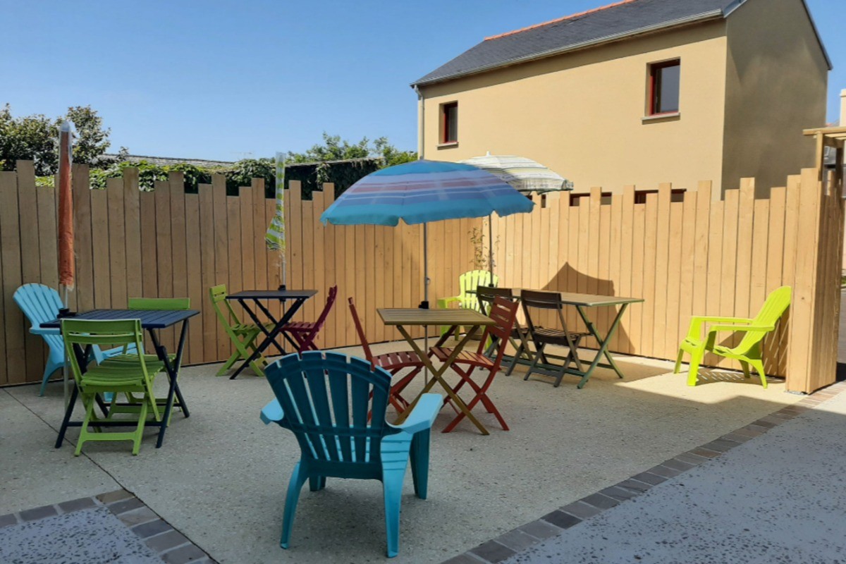 Terrasse ensoleillée avec tables de jardin. Barbecue à disposition.
