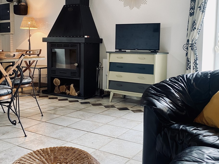 Grande pièce de vie au rez-de-chaussée avec espace cuisine toute aménagée et son mini bar, espace séjour, espace (vrai) bureau, et espace salon avec canapé en cuir, poêle à bois et TV.