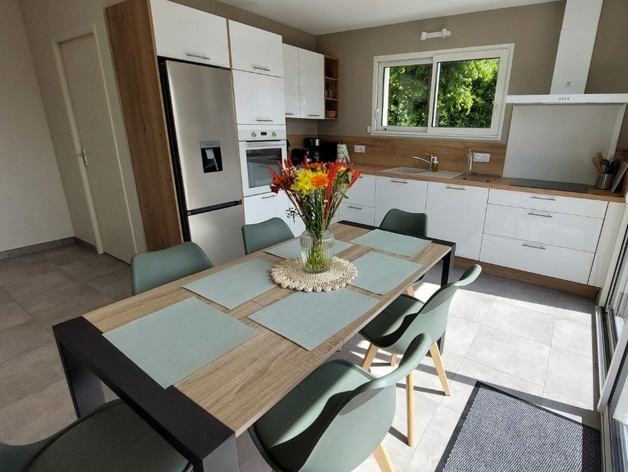 Cuisine moderne et entièrement équipée du gîte La Petite Maison, avec coin repas et baie vitrée donnant sur la terrasse.