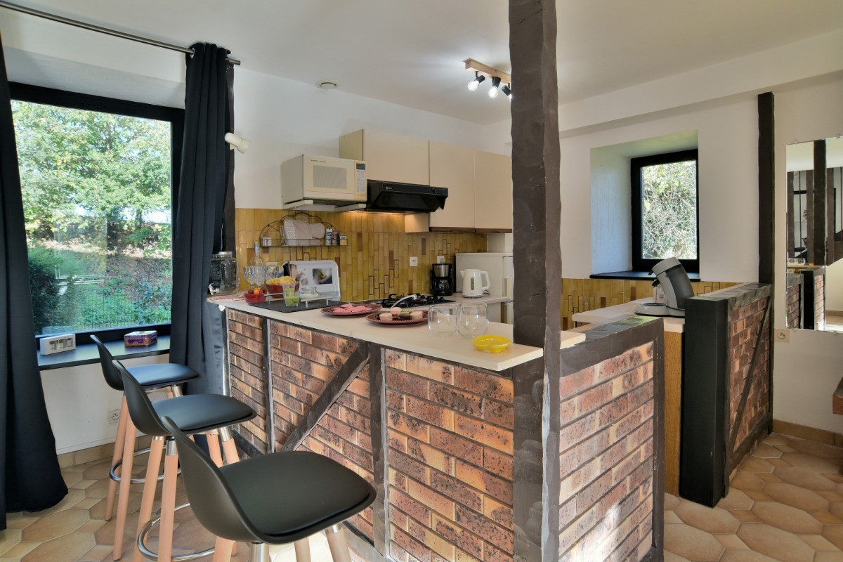 Grande pièce de vie au RDC avec coin cuisine ouverte, toute équipée et son comptoir.