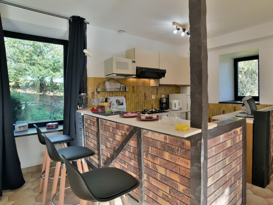 Grande pièce de vie au RDC avec coin cuisine ouverte, toute équipée et son comptoir.