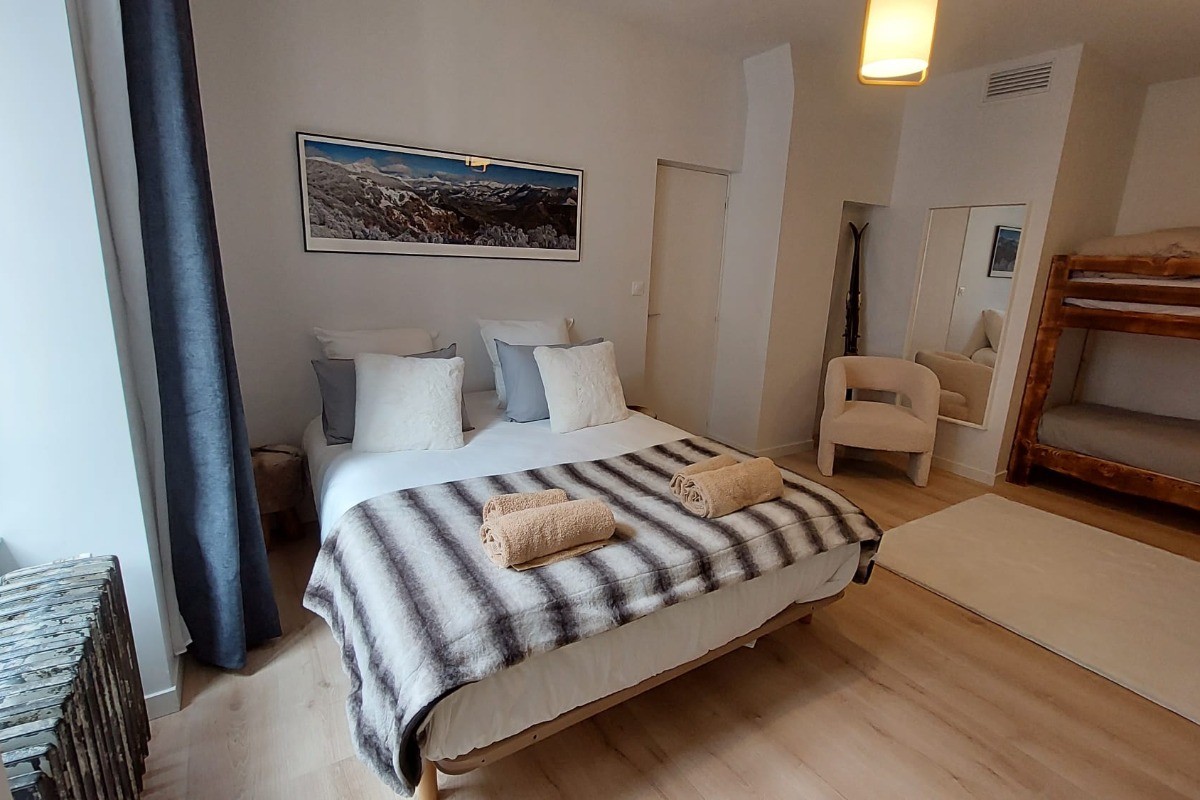 Chambre principale lumineuse avec lit double et décoration chalet