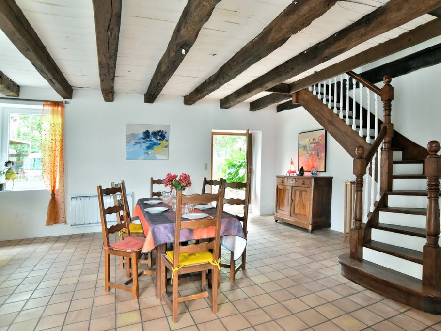 Coin séjour dans la grande pièce de vie de 62 m² et ses poutres apparentes. Accès au jardin à l'arrière de la maison.