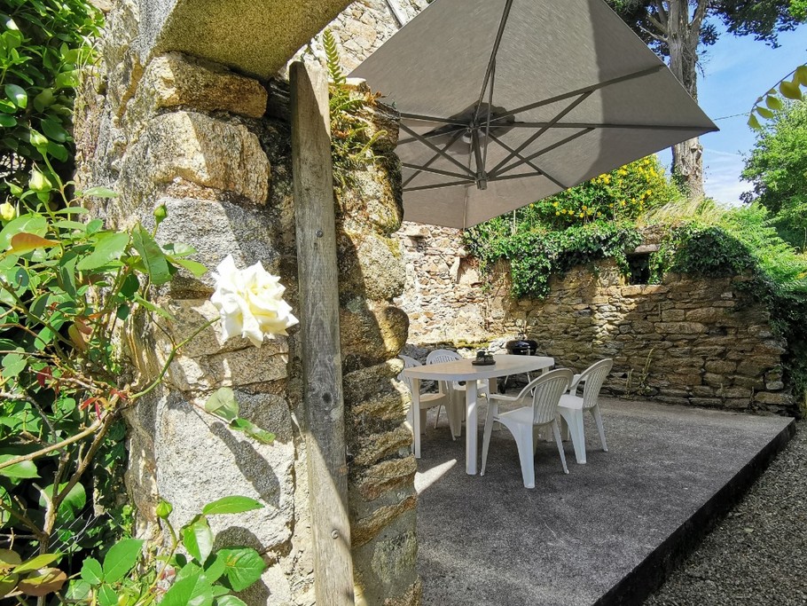 Jolie terrasse abritée avec salon de jardin, parasol, barbecue