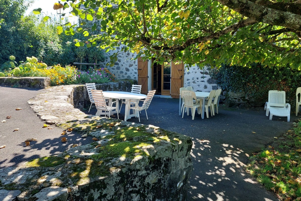 Terrasse ombragée avec table et chaises, parfaite pour des repas en plein air face à la nature.