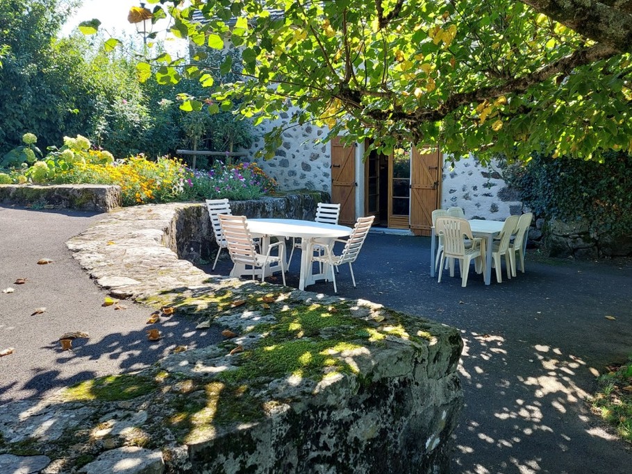 Terrasse ombragée avec table et chaises, parfaite pour des repas en plein air face à la nature.