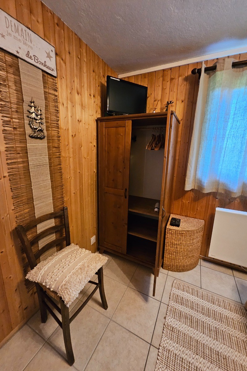 Votre chambre avec petite TV, armoire et ceintres dans une atmosphère chaleureuse