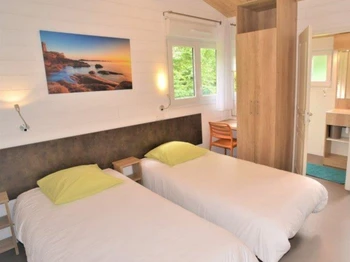 une des deux chambres de 60m², avec 2 lits simples (90×200), un WC et une salle d’eau avec douche et lavabo par chambre, un bureau, une armoire et un chauffage