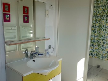 Salle de bain avec baignoire et meuble vasque. Vue mer.