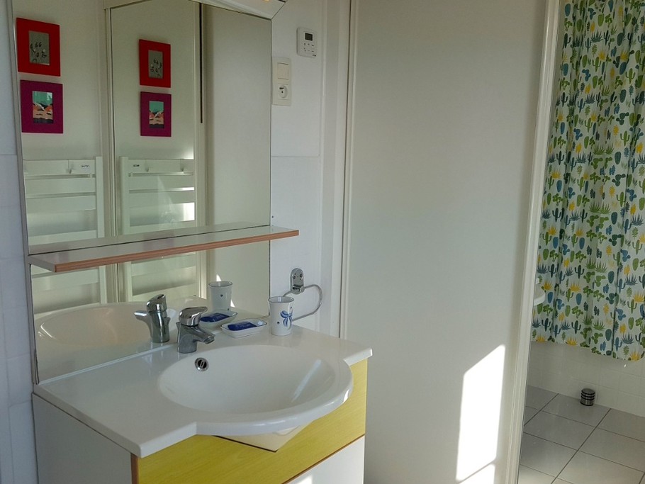 Salle de bain avec baignoire et meuble vasque. Vue mer.