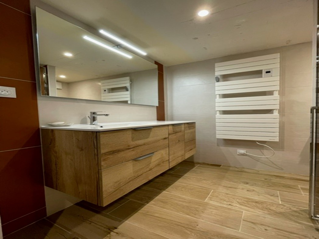 Vasque design sur plan meuble avec miroir et sèche-serviette électrique dans une salle d'eau élégante