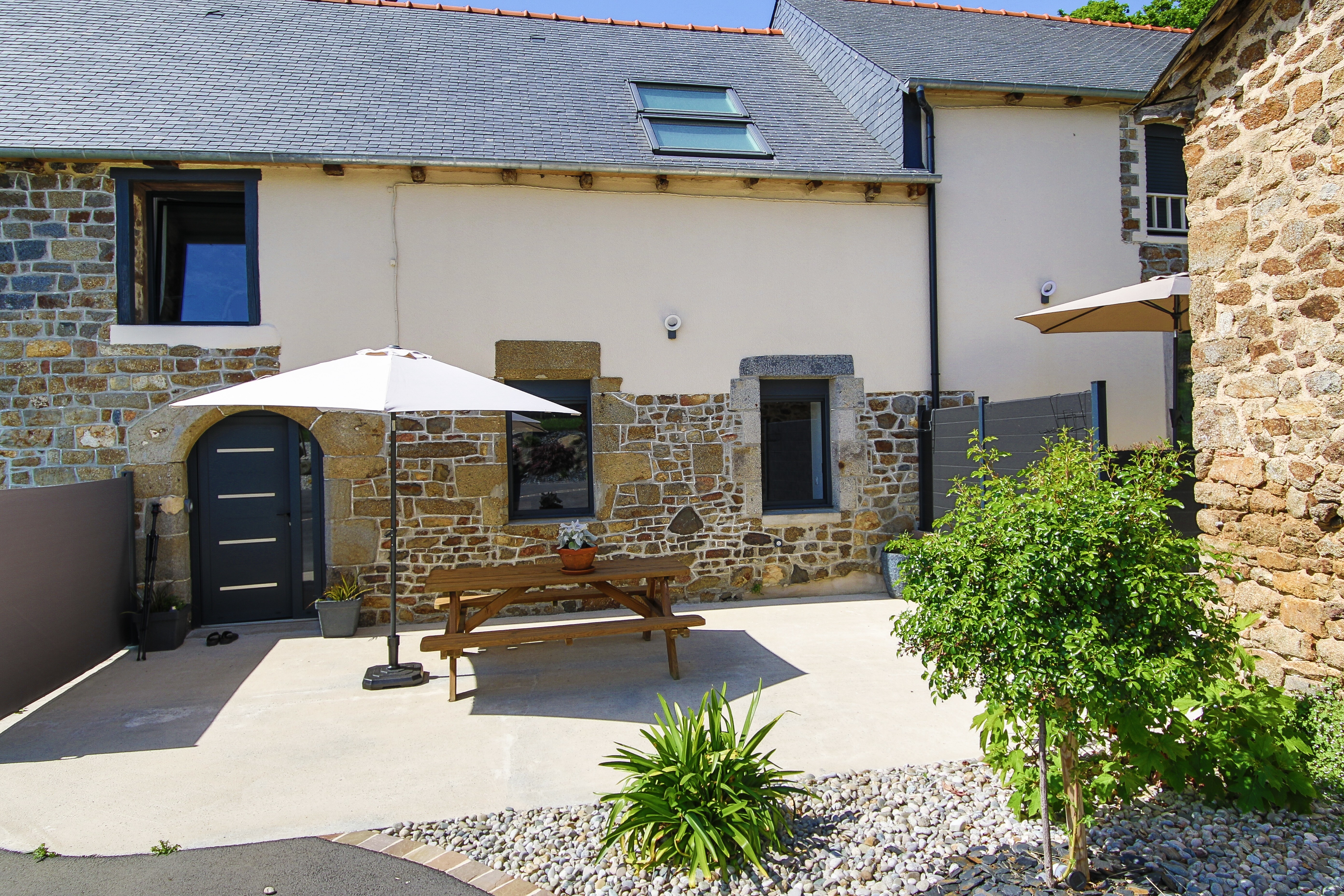 Façade du gîte avec sa terrasse. Autre gîte mitoyen à droite