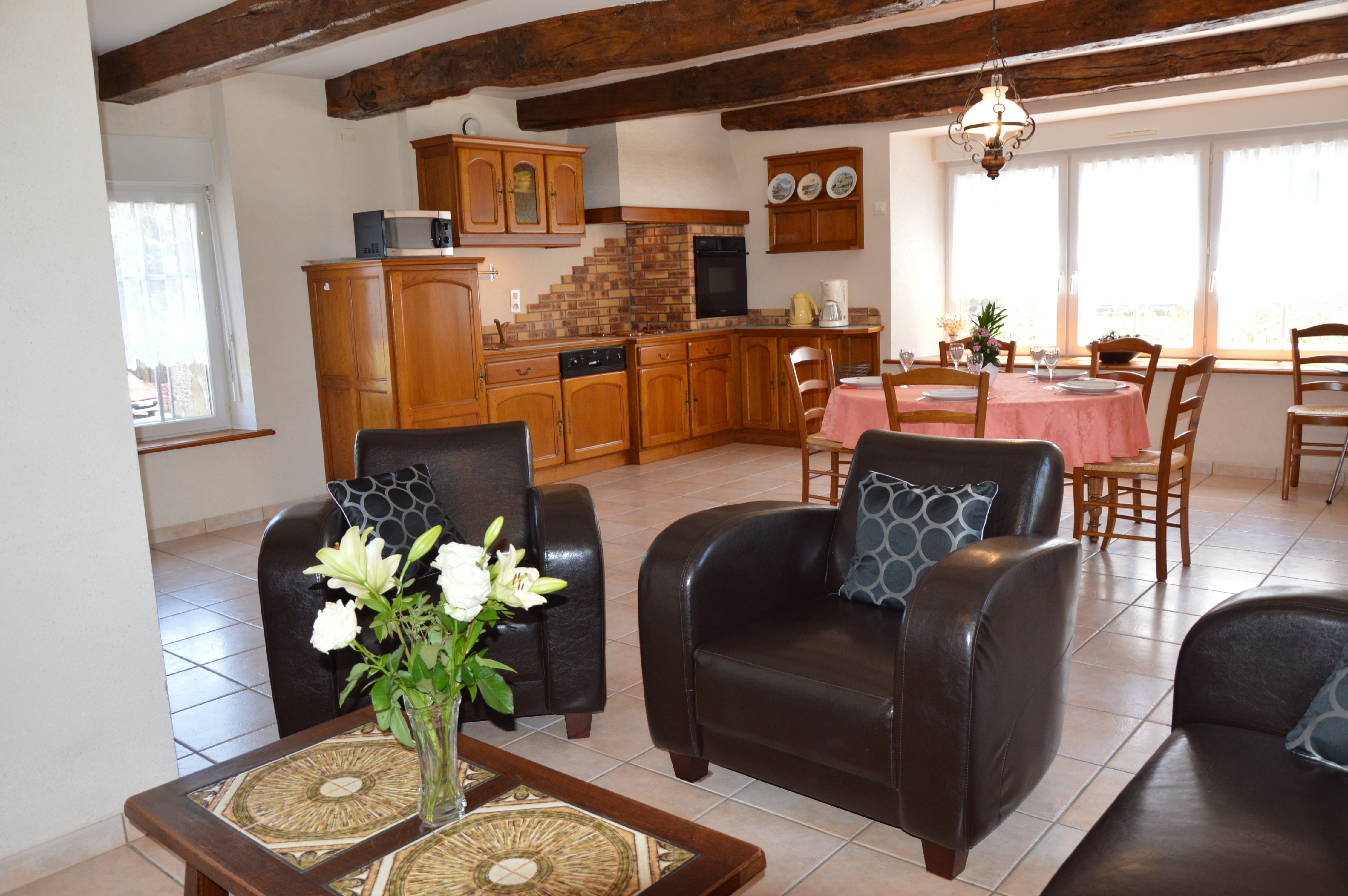 Pièce de vie agréable avec poutres apparente. Coin salon avec de confortables canapés et fauteuils en cuir. Cheminée décorative.