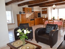 Pièce de vie agréable avec poutres apparente. Coin salon avec de confortables canapés et fauteuils en cuir. Cheminée décorative.