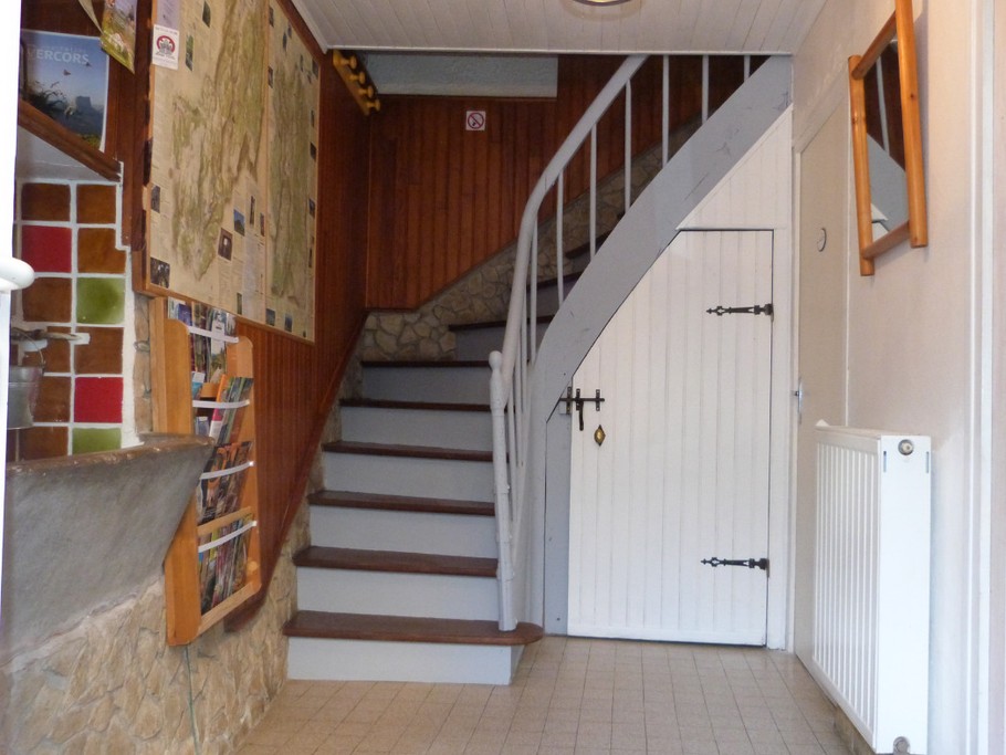 entrée du gite avec documentation et cartes. Escalier pour l'accès aux chambres